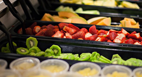 This picture has a buffet of fresh cut fruit. It has kiwi, strawberries, cantaloupe, pineapple, and watermelon.