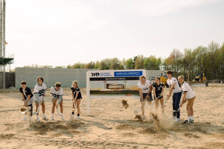 West Ottawa student athletes shoveling dirt at the stadium ground breaking event.